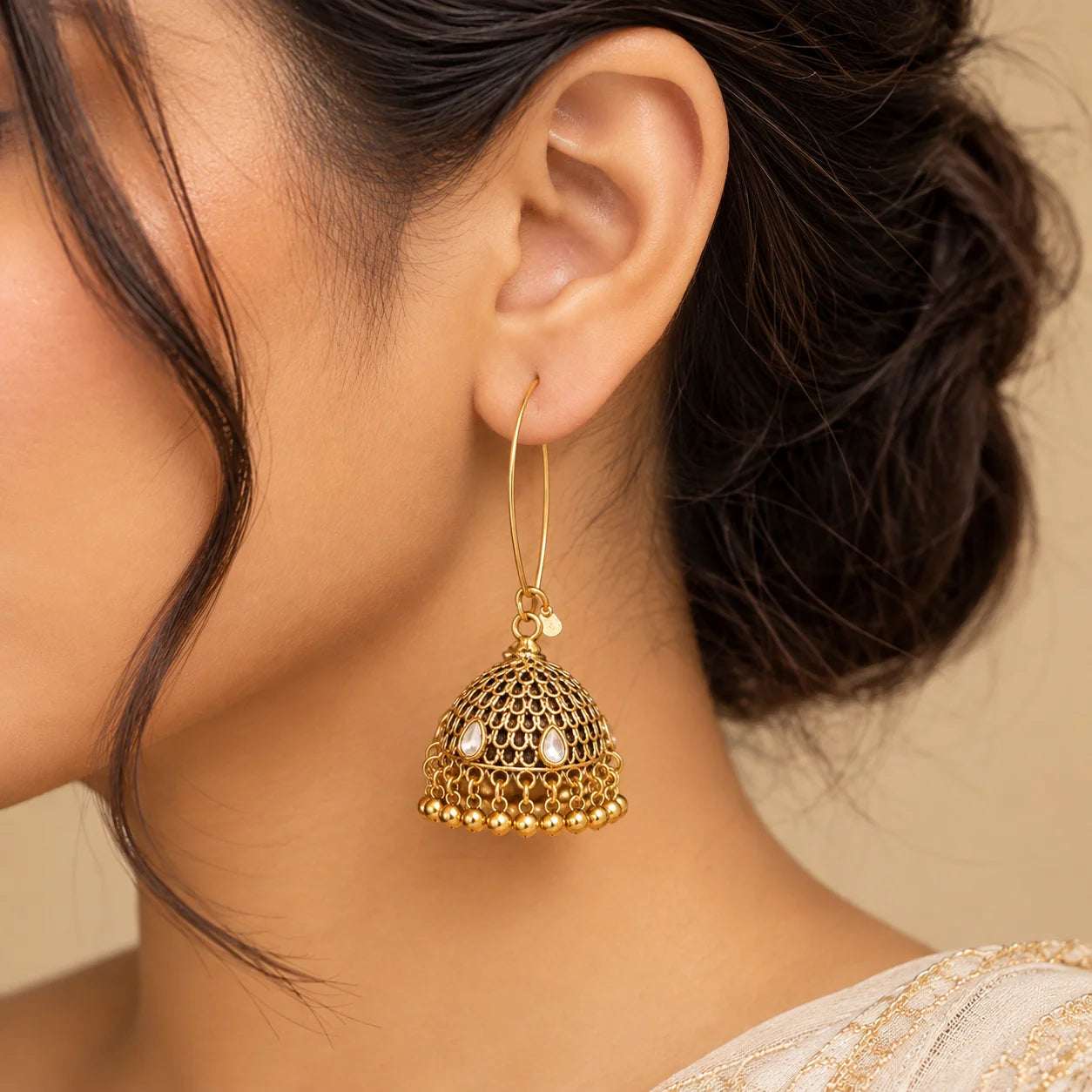 "Gold-toned antique jhumka earrings
 with intricate dome-shaped detailing, small stone accents, and a fringe of dangling gold beads."
