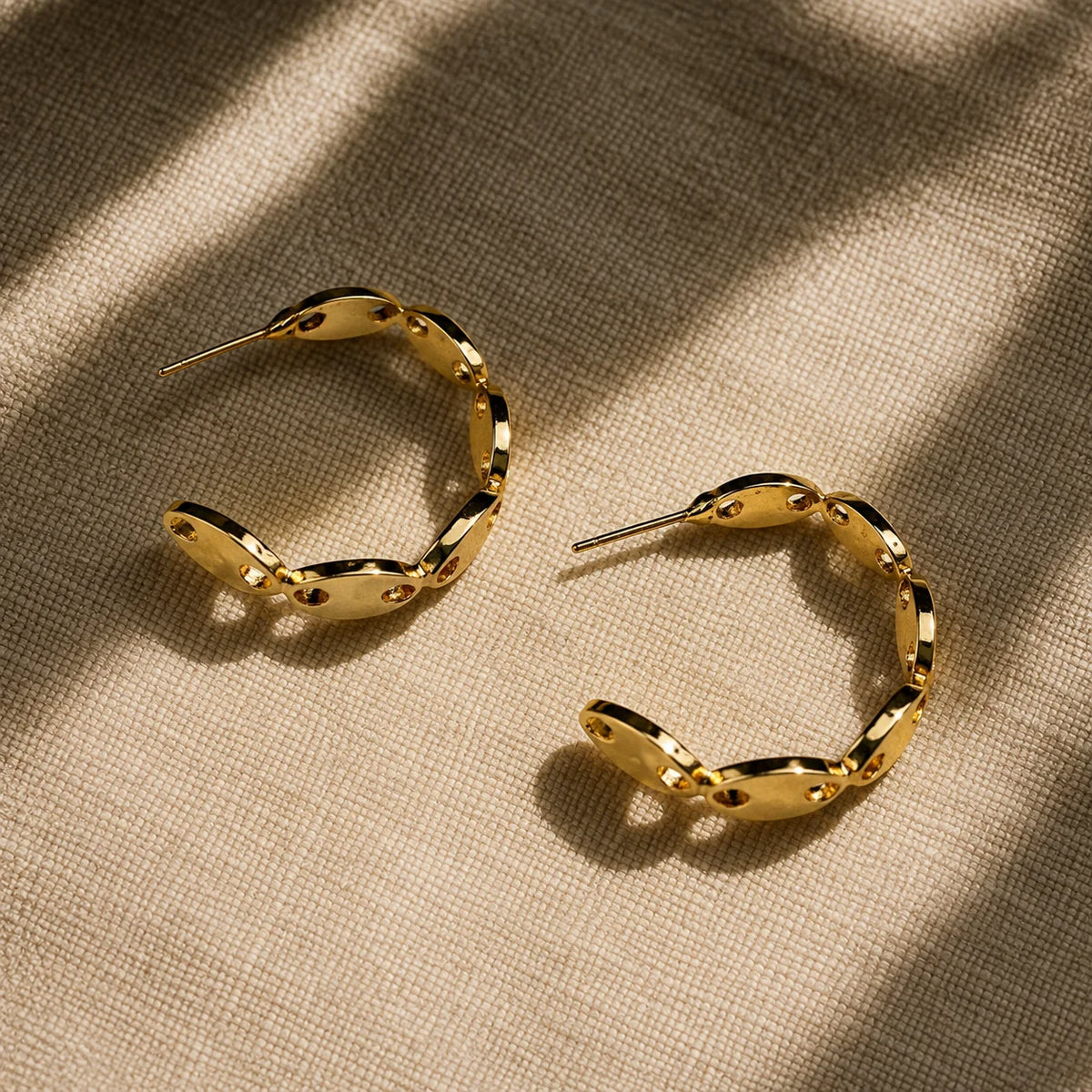 " Golden hoop earrings
 featuring a sculpted wave
design with polished gold-tone
 finish and stylish cut-out
 detailing. Lightweight 
statement earrings for
 women, perfect for everyday
 wear, office, parties, and
 festive occasions."
