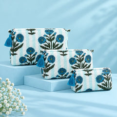 "Set of three blue and cream 
quilted pouches featuring intricate floral prints, botanical patterns, and decorative blue tassel accents."
