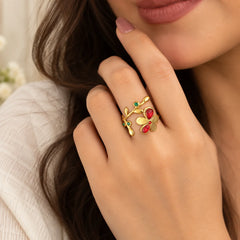 "Gold-toned open
 floral ring featuring a delicate vine design with vibrant red and green gemstone accents."
