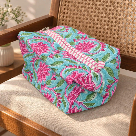 "Aqua-blue pouch
 featuring vibrant pink floral prints with green leaves and a pink-and-white striped trim, photographed on a wooden table."
