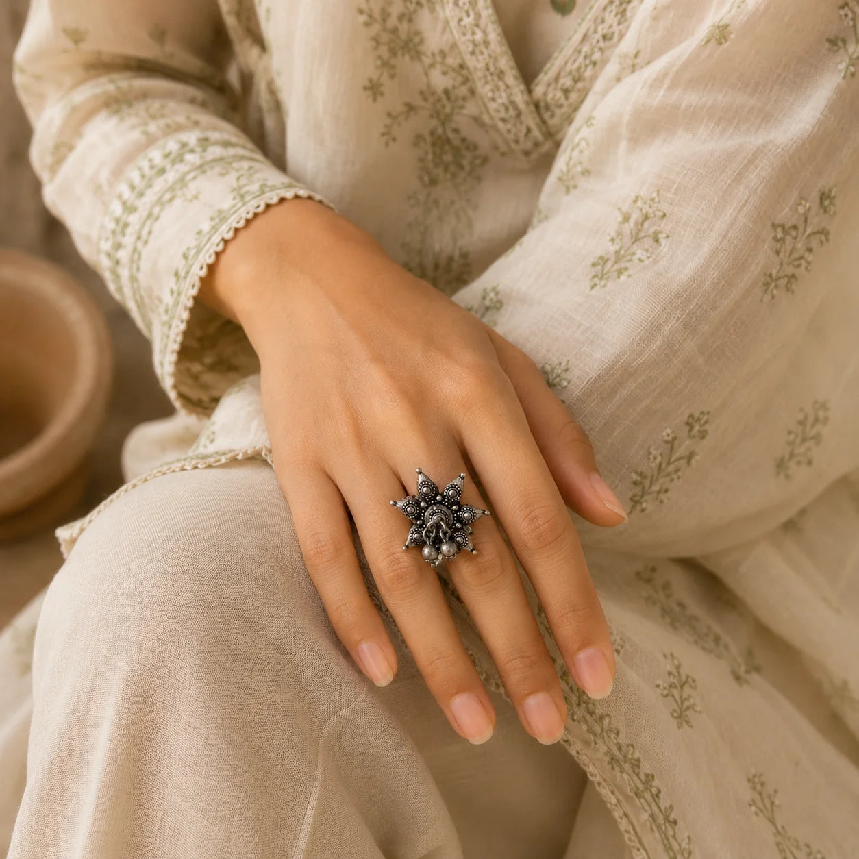 "Oxidised silver-tone
 statement ring featuring an intricate floral design, detailed textured motifs, and dangling bead accents."
