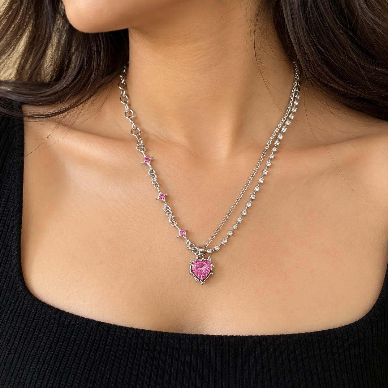 "Silver-toned necklace 
featuring a faceted pink heart-shaped centre stone, sparkling crystal accents, and delicate pink gemstone details along the chain."
