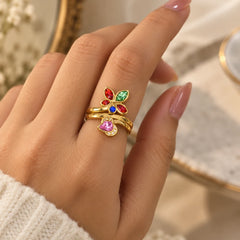 "Gold-toned floral
 ring featuring colourful pastel pink, green, purple, and peach stones in a delicate open vine-inspired design, shown worn on a finger."
