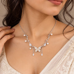 "Silver-toned butterfly 
necklace with a delicate chain, pearl-like bead accents, sparkling teardrop details, and dangling chain extensions"
