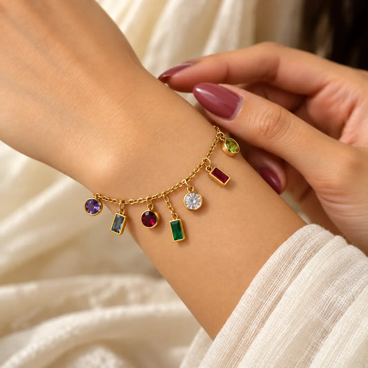 "Gold-toned chain
 bracelet featuring colorful gemstone-style charms in green, red, purple and clear shades, with round and rectangular accents and an adjustable extension chain."
