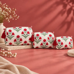 "Set of quilted fabric
 pouches with a white base, red floral and green leaf print, purple accents, and decorative red tassels."
