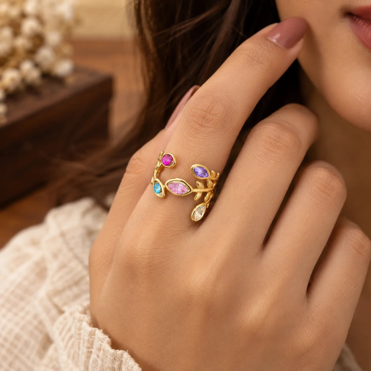 "Gold-toned open 
vine ring featuring colourful pink, purple, blue, green, and red gemstone accents in a delicate floral-inspired design."
