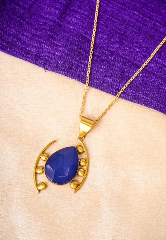 Stylish metal curb chain necklace with an organic-shaped pendant, enhanced with faceted blue teardrop stones, having a polished gold-tone finish, and a secure lobster claw clasp