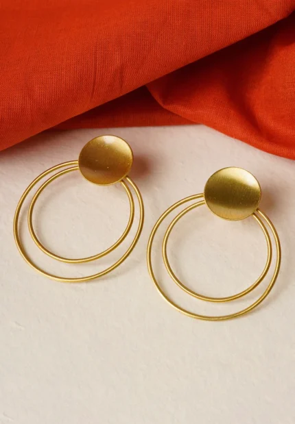 Modern brass drop earring with a sculptural design, showcasing an triangular-shaped top with a hollow center, two interlinked hoops, and a textured triangle charm gracefully dangling at the bottom, secured with a push-back closure.