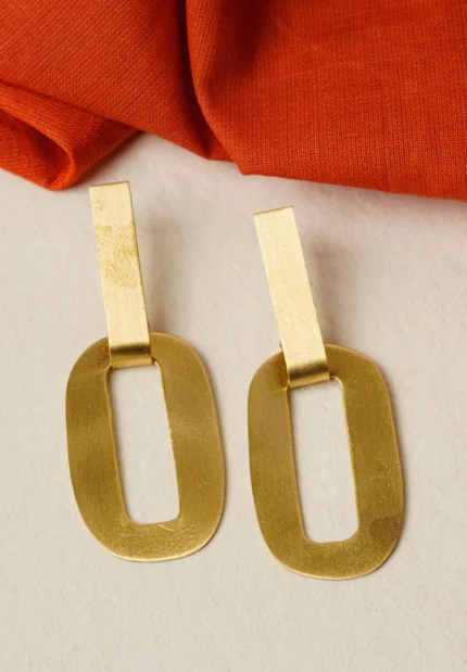 Modern brass drop earring with a sculptural design, showcasing an oval-shaped top with a hollow center, two i+CF300nterlinked hoops, and a textured triangle charm gracefully dangling at the bottom, secured with a push-back closure