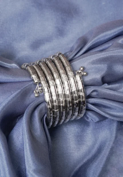 Contemporary metal spiral bracelet with a refined gold/silver texture, showcasing a multi-layered structure and bead details at both edges.