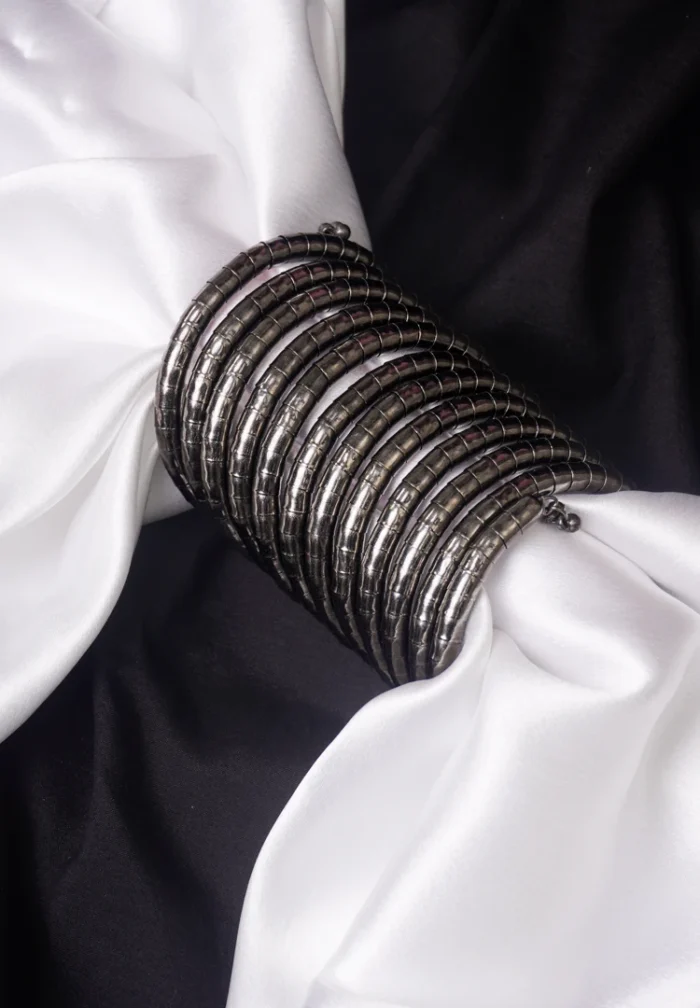 Contemporary metal spiral bracelet with a refined gold/silver texture, showcasing a multi-layered structure and bead details at both edges