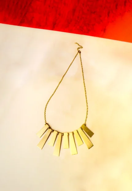 Stylish metal curb chain necklace with an organic-shaped pendant, enhanced with faceted blue teardrop stones, having a polished gold-tone finish, and a secure lobster claw clasp
