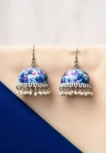 Elegant silver-finish jhumka earring with butterfly meenakari artwork, a detailed circular top, pearl bead accents, and a secure push-back closure.