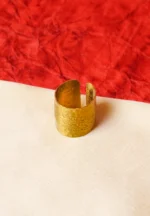 Elegant gold-tone ring featuring a cylindrical shape having a open-end design, and fine moulded texture with complex details