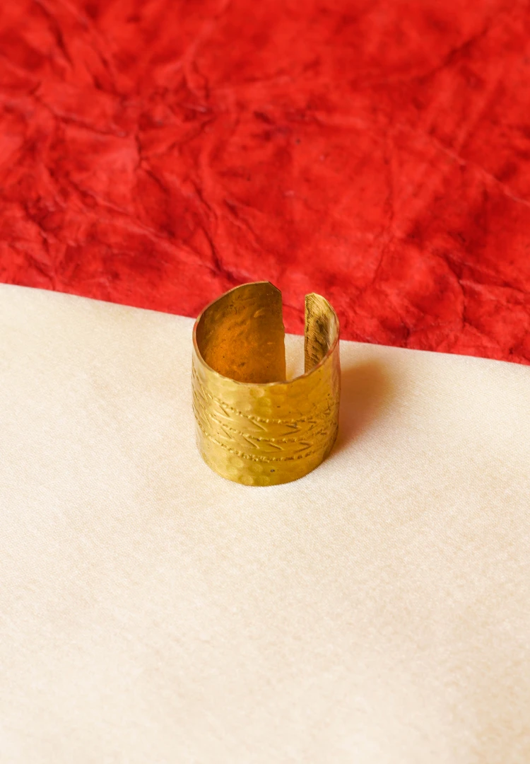 46-Th Elegant gold-tone ring featuring a cylindrical shape having a open-end design, and fine moulded texture with complex details