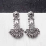 Traditional oxidized silver dangle earring featuring a finely crafted floral top detailing with gold-toned , elegant crescent shaped, and symmetrical geometric elements adorned with ghungroos at the end, and push back post.