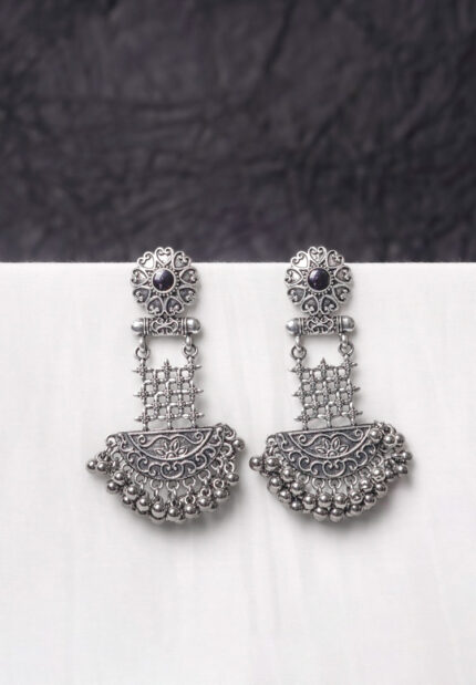 Traditional oxidized silver dangle earring featuring a finely crafted floral top detailing with gold-toned , elegant crescent shaped, and symmetrical geometric elements adorned with ghungroos at the end, and push back post.
