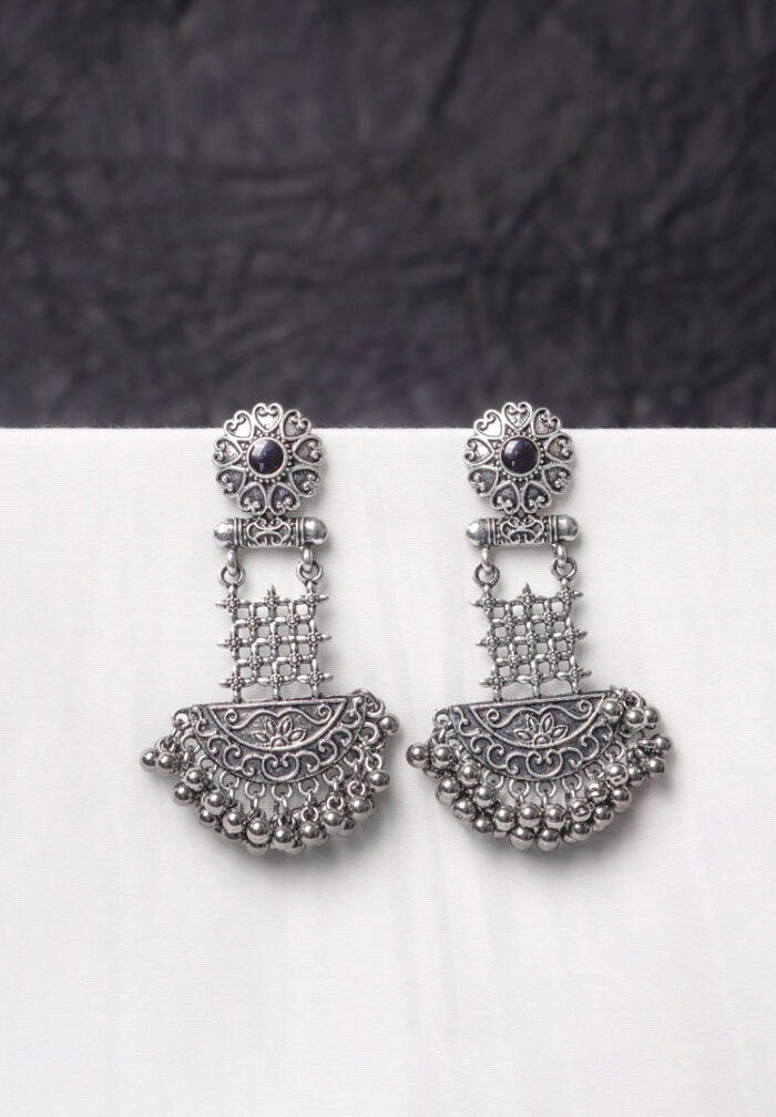 Traditional oxidized silver dangle earring featuring a finely crafted floral top detailing with gold-toned , elegant crescent shaped, and symmetrical geometric elements adorned with ghungroos at the end, and push back post.