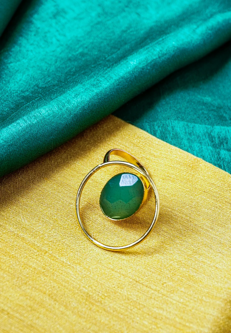 51-Th Modern geometric ring with a polished gold-tone finish also a round wire structure, and a emerald-green stone in the middle