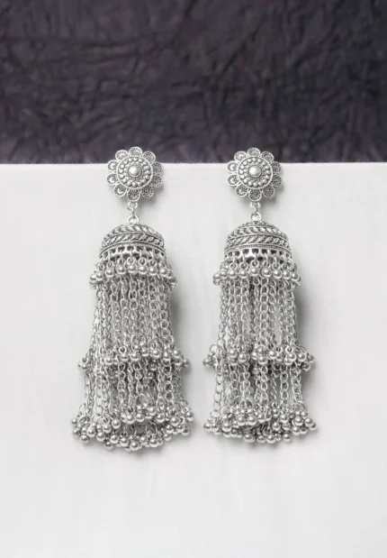 Oxidised jhumka earrings with complex floral detailing, featuring a finely detailedchain tassels, and ghungroos at the bottom, secured with a curved hook closure.