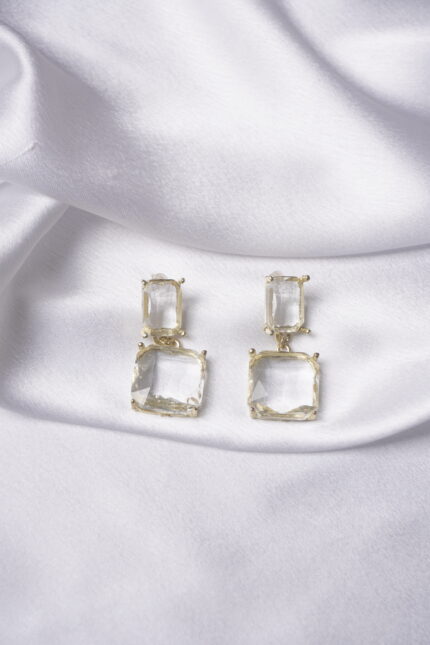 Sleek gold-tone dangle earrings with two slinging rectangular clear crystals, each with a soft golden hue, fastened with a push back post