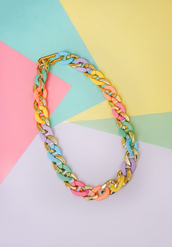 Fashion-forward necklace with a bold chain-link design, featuring gold-tone and vibrant multicolor metal links, secured with a golden hook clasp.