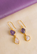 Modern asymmetrical teardrop-shaped metal dangle earrings with a gold tone and white/purple finish, featuring dual interconnected teardrop elements and raw gemstones with a soft shimmer, secured with a curved hook closure