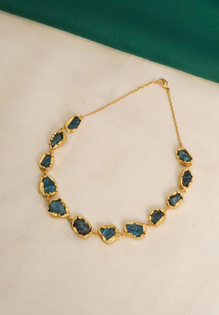Flat cable chain choker necklace with a polished golden tone/emerald finish, featuring evenly spaced irregular organic-shaped purple raw gemstones and a lobster claw clasp