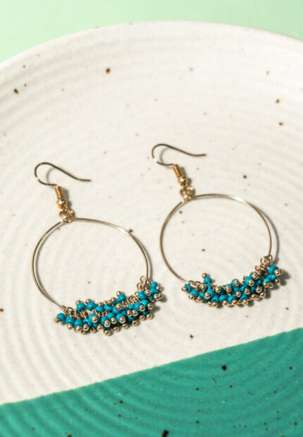 Chic metal hoop earrings featuring a polished gold-tone finish, playful turquoise enamel accents, also mini beads and a push back for easy wear