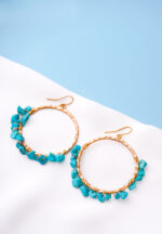 Chic metal hoop earrings featuring a polished gold-tone finish, playful turquoise beaded accents, and a curved hook back for easy wear.