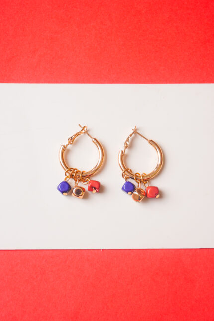 Chic metal hoop earrings featuring a polished gold-toneburnt umber finish featuring golden blue and brick coloured mini cube shaped chrams at the bottom, and a hinged back for easy wear.