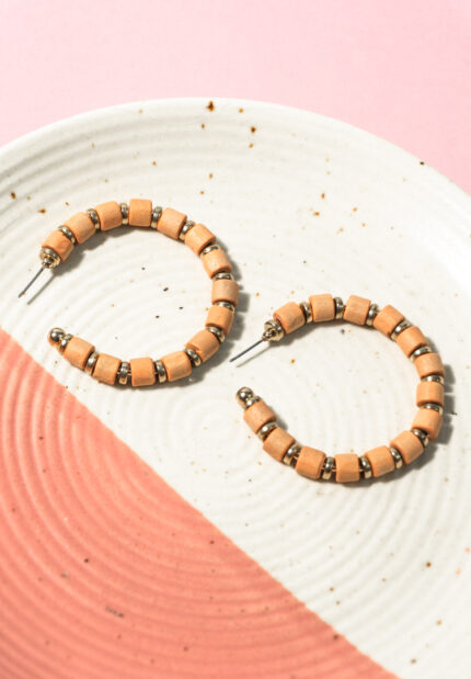 Chic metal hoop earrings featuring a polished gold-tone pearls, with peach coloured wooden beads along with small circular golden beads a push back for easy wear.