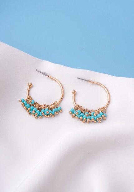 Chic metal hoop earrings featuring a polished gold-tone finish,/turquoise finish featuring dangling turquoise coloured mini beads at the curve , and a push back for easy wear