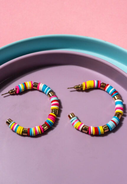 Chic metal hoop earrings featuring a polished gold-tone finish, playful colorful beads accents, following stripped pattern and a endless back.