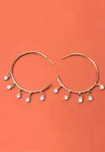 Trendy mini C-hoop earring with a polished gold-tone/pearl finish, adorned with a dangling clear gemstones and , push-back post.