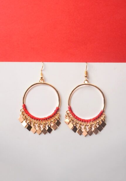 Chic metal hoop earrings featuring a polished golden-tone finish/crimson red,cherry red finish adorned with red coloured tread wrapped in the bottom with dangling small diamond-shaped golden charms and french hook closure.
