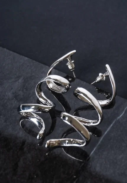 Sleek and contemporary dangle earrings with a coiled spiral structure, finished in a silver tone and secured with a push-back post.