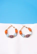 Chic metal hoop earrings featuring a polished golden-tone finish, /burnt umber,sky blue,coffee finish adorned with multicoloured square shaped beads with circular golden beads and a hinged back.