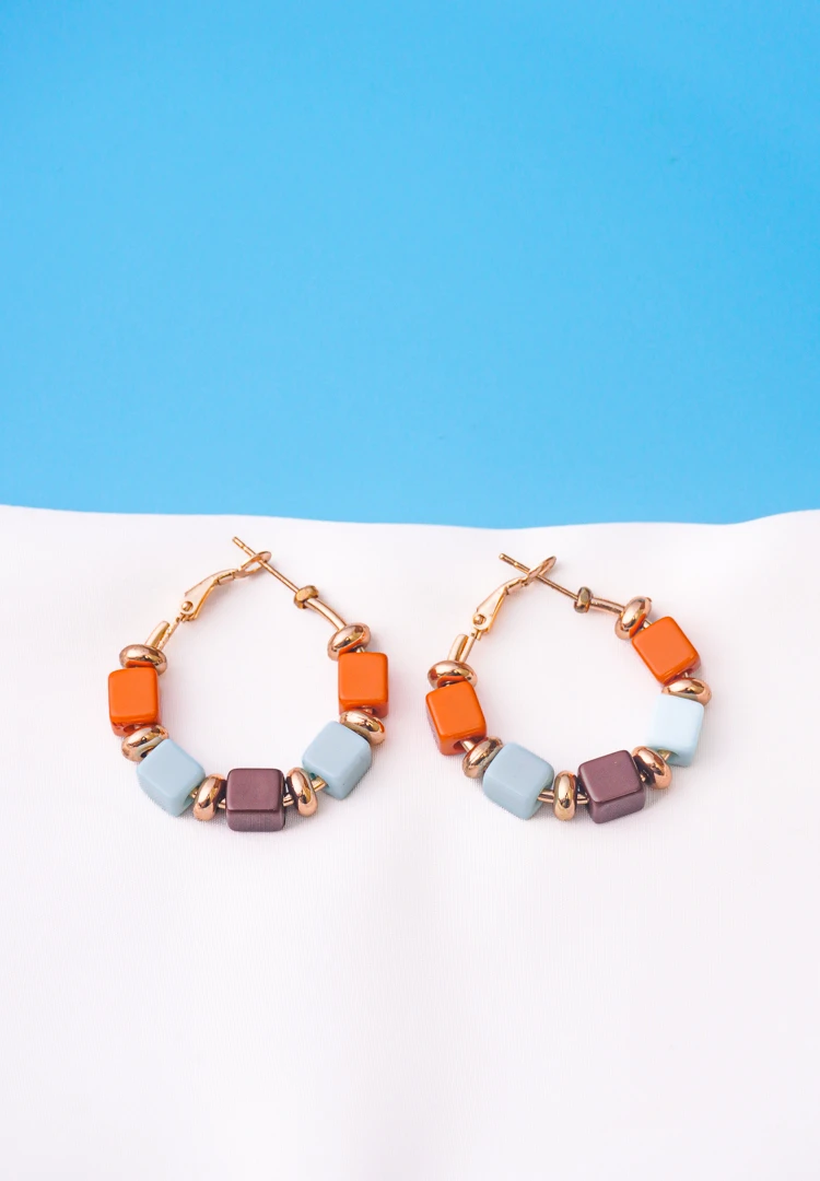 223-1 Chic metal hoop earrings featuring a polished golden-tone finish, /burnt umber,sky blue,coffee finish adorned with multicoloured square shaped beads with circular golden beads and a hinged back.