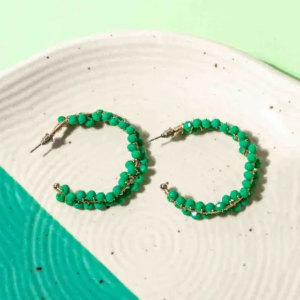 Chic metal hoop earrings featuring a polished golden-tone finish,/teal blue finish adorned with small green beads intricately threaded and wrapped around the frame with a endless back.