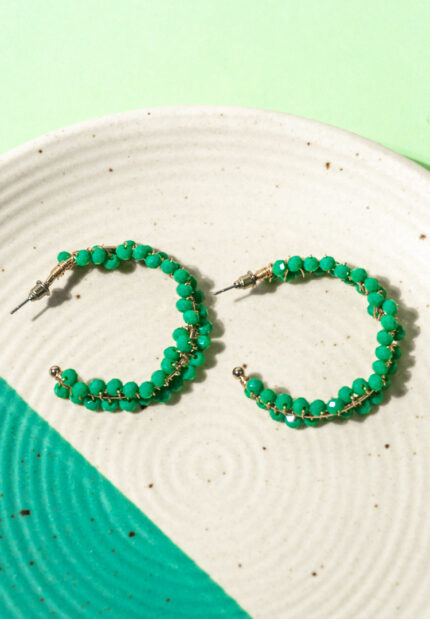Chic metal hoop earrings featuring a polished golden-tone finish,/teal blue finish adorned with small green beads intricately threaded and wrapped around the frame with a endless back.