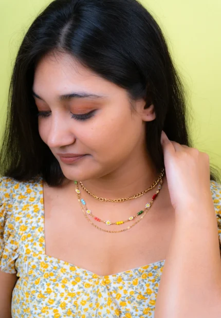 Modern three-tier curb chain necklace with a structured thick upper chain and two dainty lower chains, enhanced by multicolored beadwork and floral designs, secured with a lobster clasp