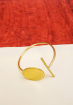 Modern geometric ring with a polished gold-tone finish also a round wire structure, and a emerald-green stone in the middle