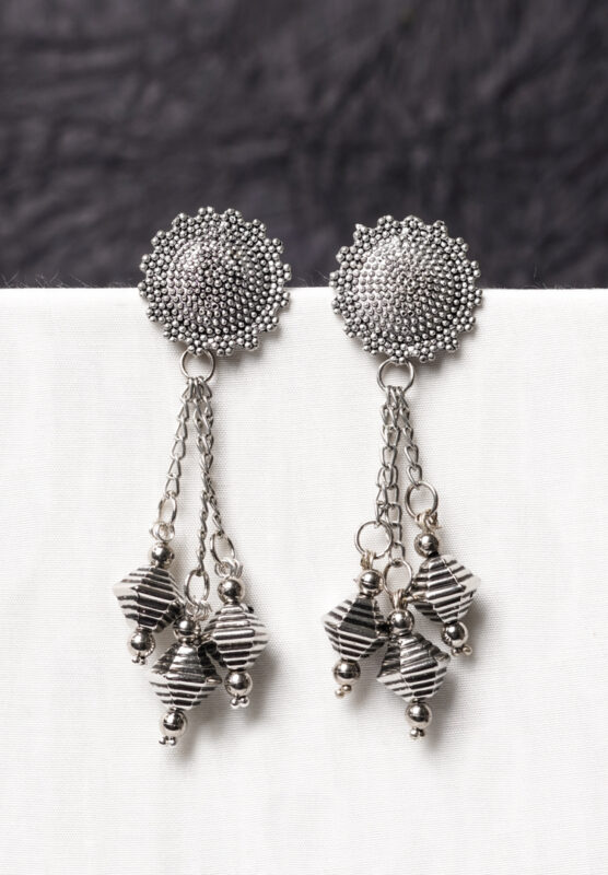 Traditional oxidized silver dangle earring featuring a finely crafted circular top, elegant chain tassels, and symmetrical geometric elements adorned with tiny bead accents
