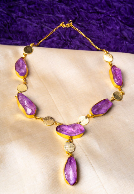 Modern brushed gold and purple curb chain necklace featuring free form raw gemstones, metallic disc details, and a lobster claw clasp for secure wear