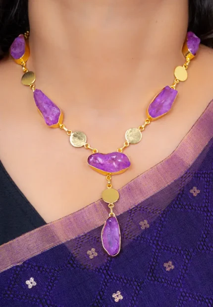 Modern brushed gold and purple curb chain necklace featuring free form raw gemstones, metallic disc details, and a lobster claw clasp for secure wear