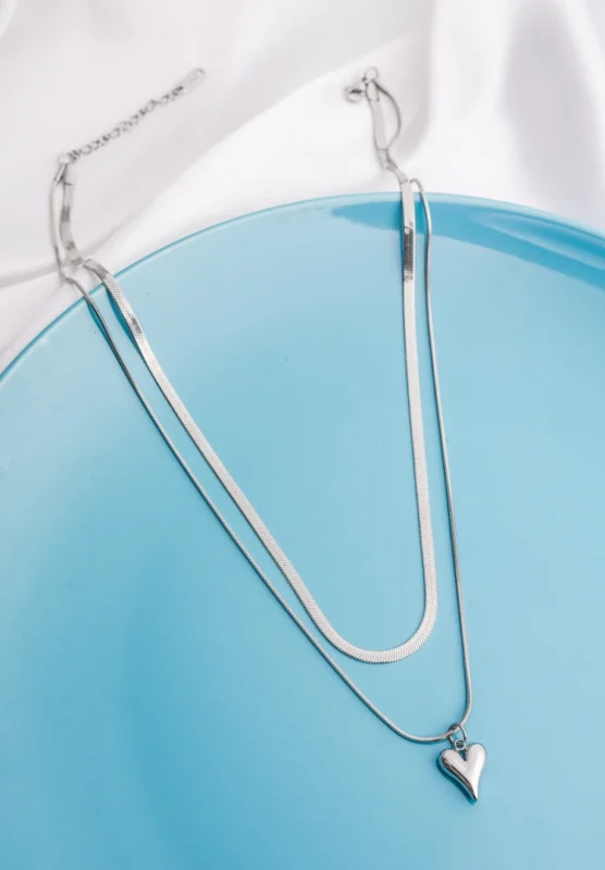 Modern two layered snake chain necklace with a polished silver finish, a solid heart charm, and an adjustable lobster clasp.