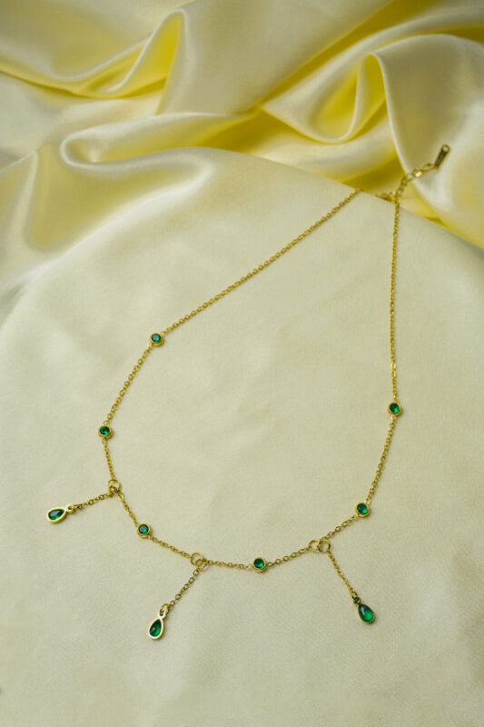 Stylish gold-tone necklace with a filled flat cable chain, an elegant teadrop shaped pendant,with delicate filigree and a green stone in the center and a lobster claw clasp